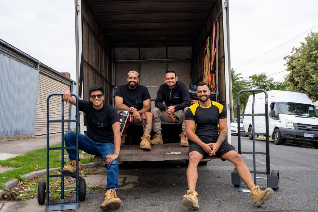 Removalists team sitting in the back of a moving truck with hand trolleys, ready for a house move in Australia