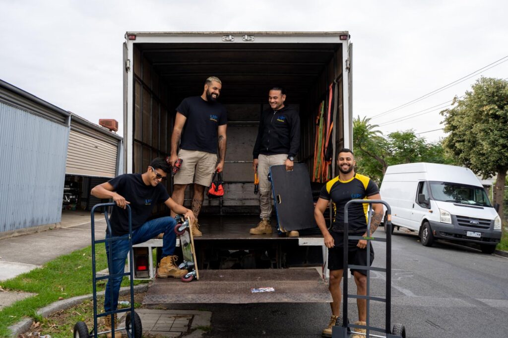 Professional removalists team at the back of a moving truck with dollies and equipment, ready for a house move