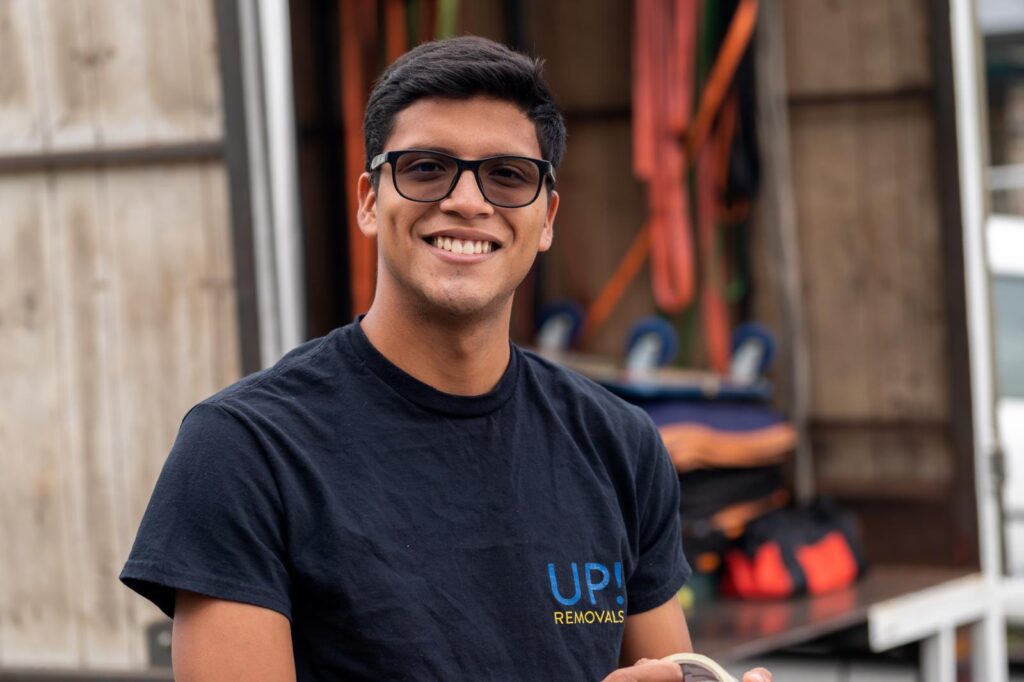 Friendly removalist in uniform smiling near a moving truck, ready for a house relocation in Australia