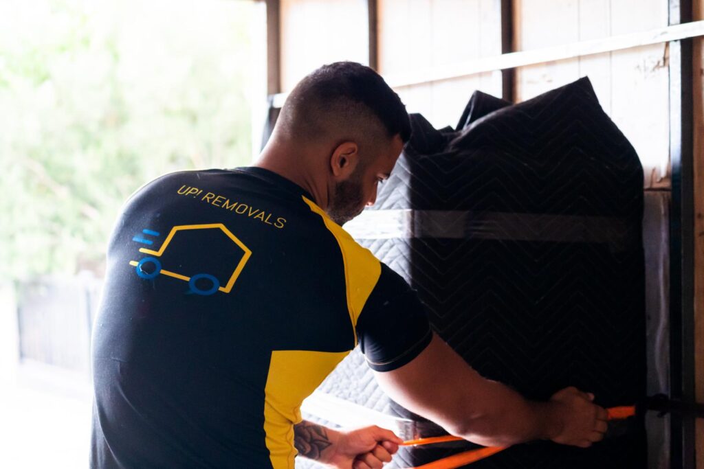 UP! Removals mover securing wrapped furniture inside a moving truck for safe house relocations in Victoria and Perth