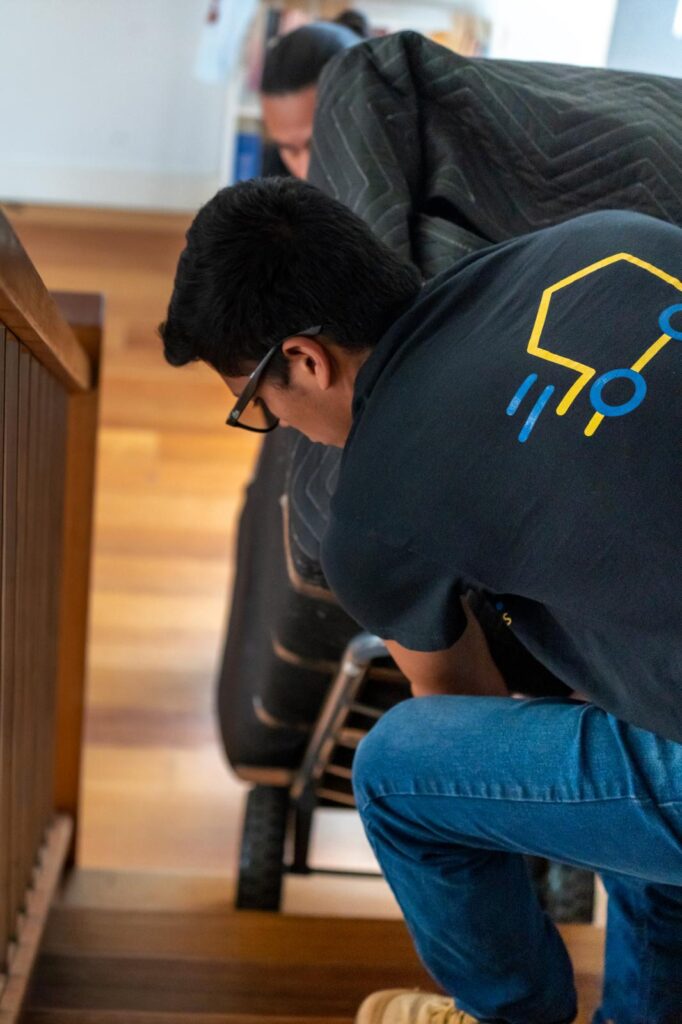 UP! Removals team moving a sofa upstairs with protective blankets during a home relocation