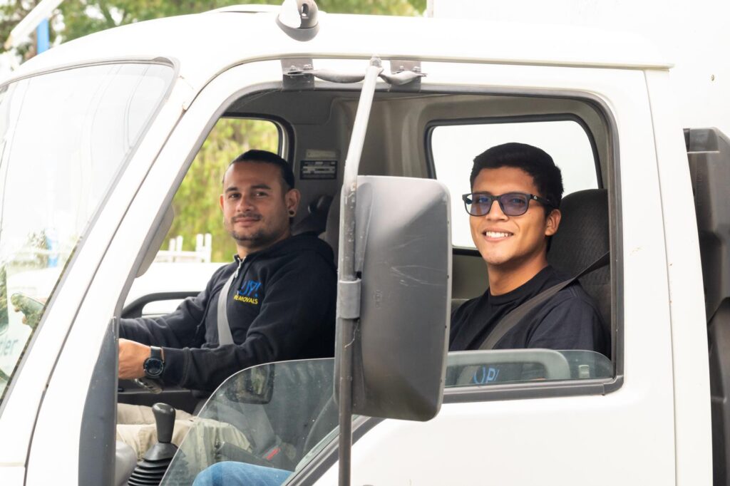 Friendly removalists in a moving truck cab ready for a home relocation service in Australia