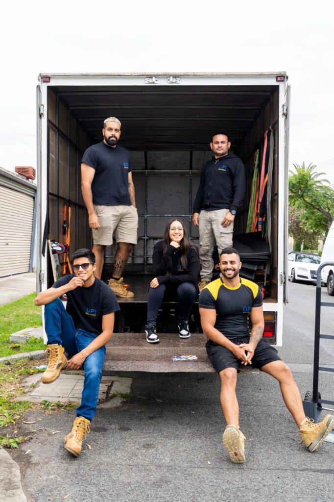 Friendly removalists team sitting in the back of a moving truck ready for a home relocation in Australia