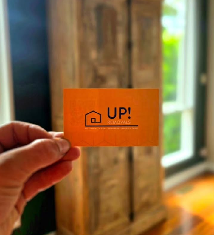 Removal company business card held in hand inside a home during a moving service in Australia