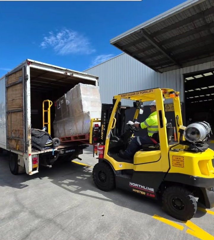 Forklift loading a large wrapped pallet into a truck for commercial relocations and logistics
